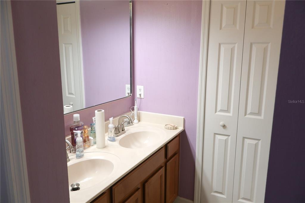 A bathroom features a double-sink vanity with wood cabinets and a large wall mirror — 5396 CARAMELLA DRIVE, ORLANDO, FL
