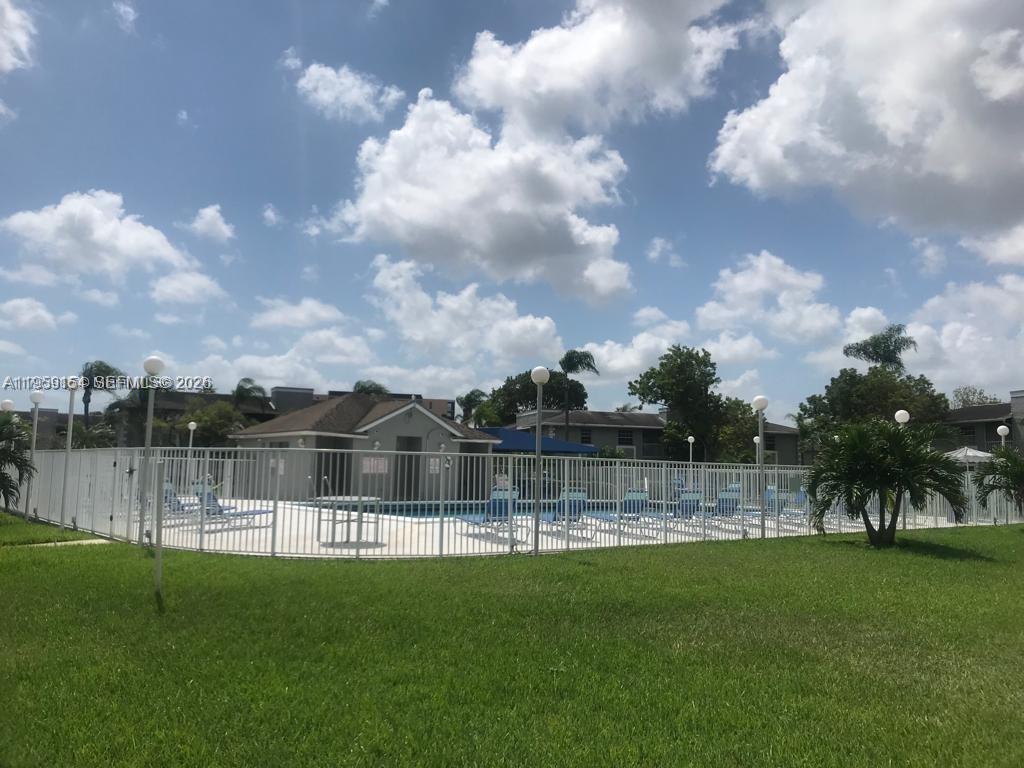 A fenced outdoor swimming pool area with lounge chairs and a small building — 439 NE 210th Cir Ter # 22, Miami FL 33179, MIAMI, FL