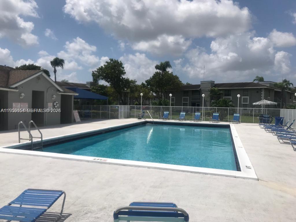 An outdoor swimming pool is surrounded by a concrete deck and lounge chairs — 439 NE 210th Cir Ter # 22, Miami FL 33179, MIAMI, FL