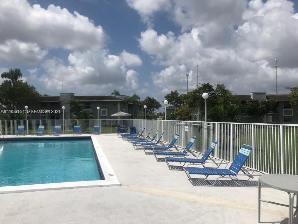 A swimming pool with lounge chairs sits on a concrete deck beside apartment buildings — 439 NE 210th Cir Ter # 22, Miami FL 33179, MIAMI, FL