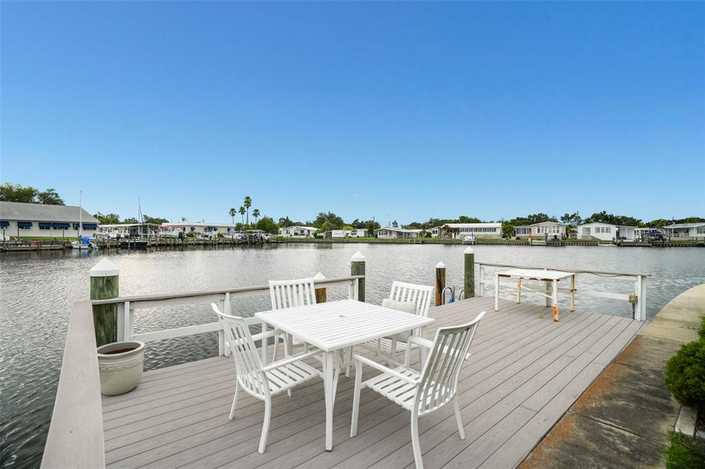 A white patio table and four chairs sit on a wooden deck overlooking a canal — 7162 MOUNT ARLINGTON DRIVE NE UNIT 417, ST PETERSBURG, FL