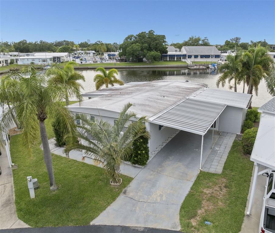 An elevated view of a single-story mobile home with a carport and waterfront backyard — 7162 MOUNT ARLINGTON DRIVE NE UNIT 417, ST PETERSBURG, FL