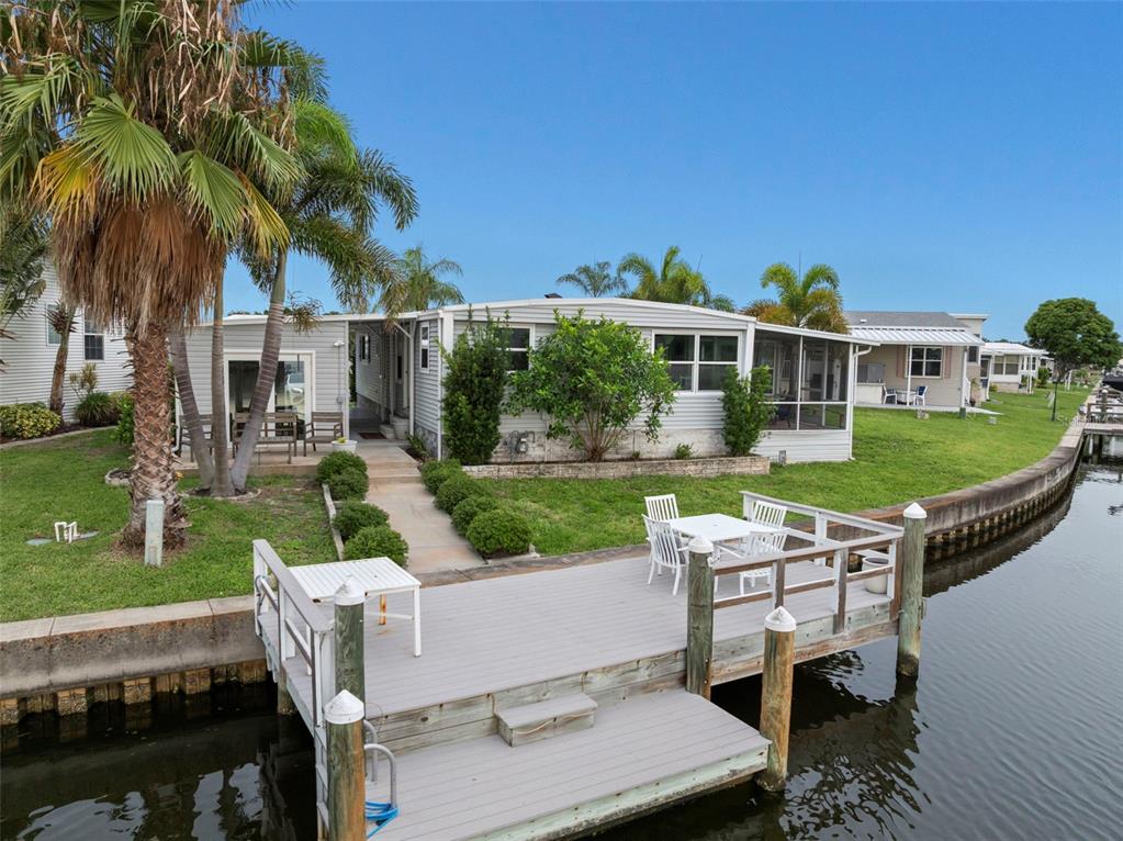 A mobile home sits along a canal with a wooden dock and a palm tree — 7162 MOUNT ARLINGTON DRIVE NE UNIT 417, ST PETERSBURG, FL