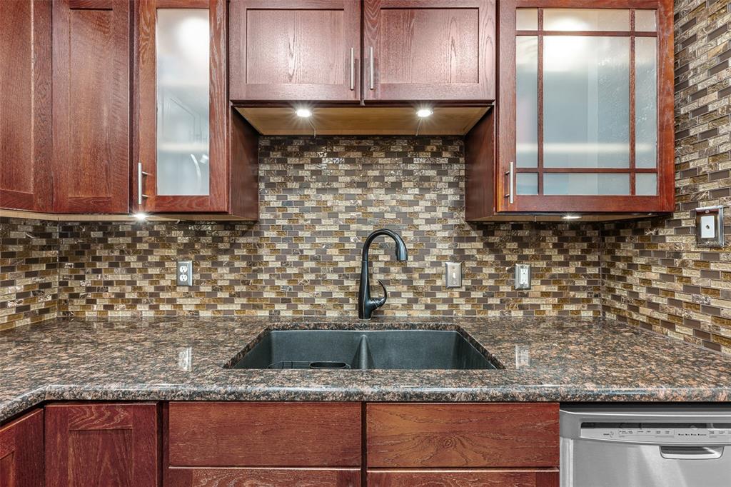 A kitchen sink area features dark wood cabinets, granite countertops, and a mosaic tile backsplash — 9481 HIGHLAND OAK DRIVE UNIT 1709, TAMPA, FL