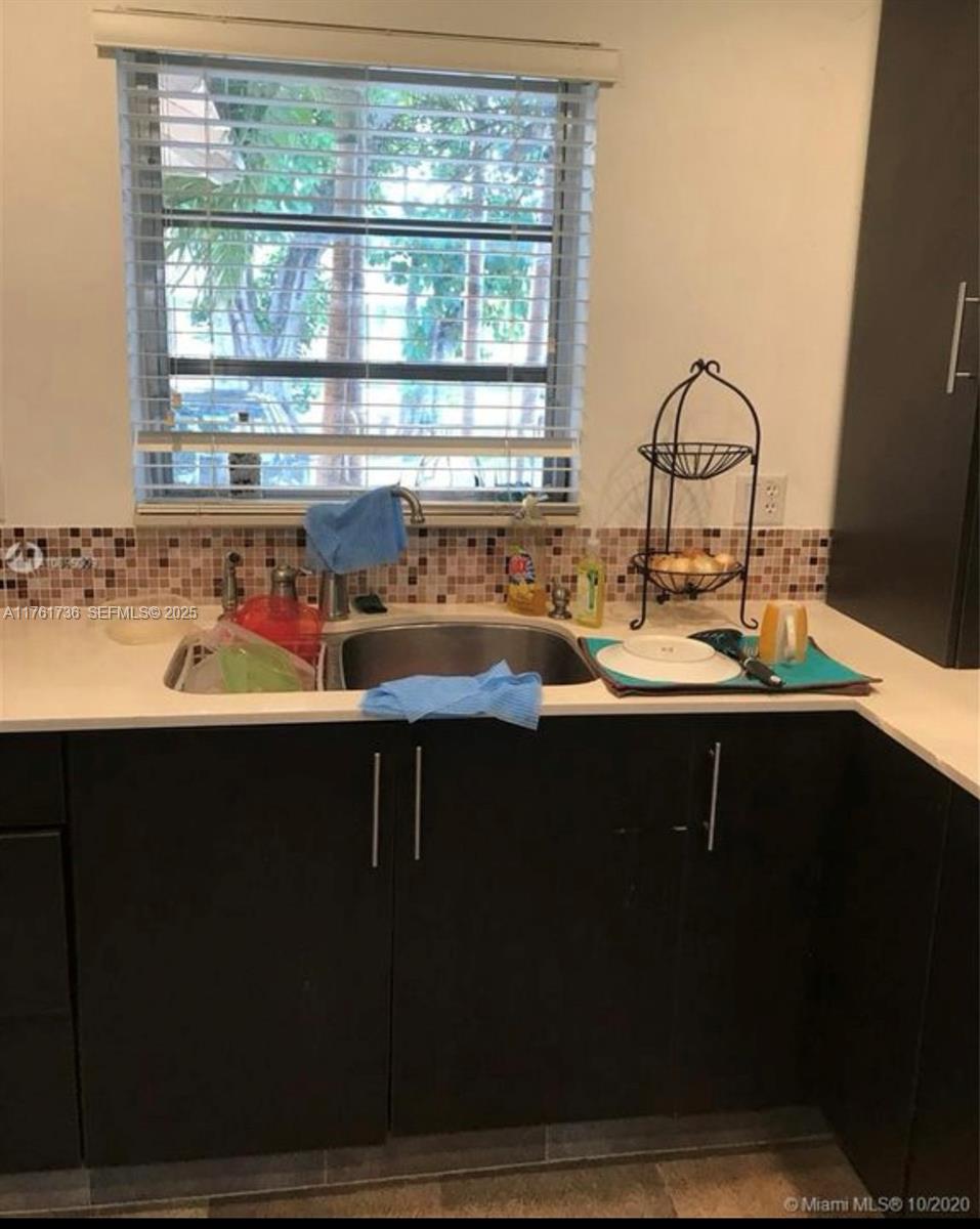 A kitchen sink area features dark cabinets, a white countertop, and a tiled backsplash — 7344 SW 82nd St # C113, Miami FL 33143, MIAMI, FL