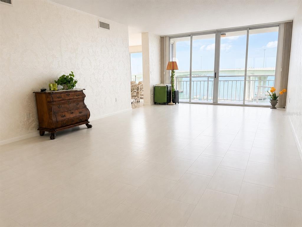 A bright living room features light tile flooring, a wooden chest, and a balcony overlooking water — 100 PIERCE STREET UNIT 808, CLEARWATER, FL