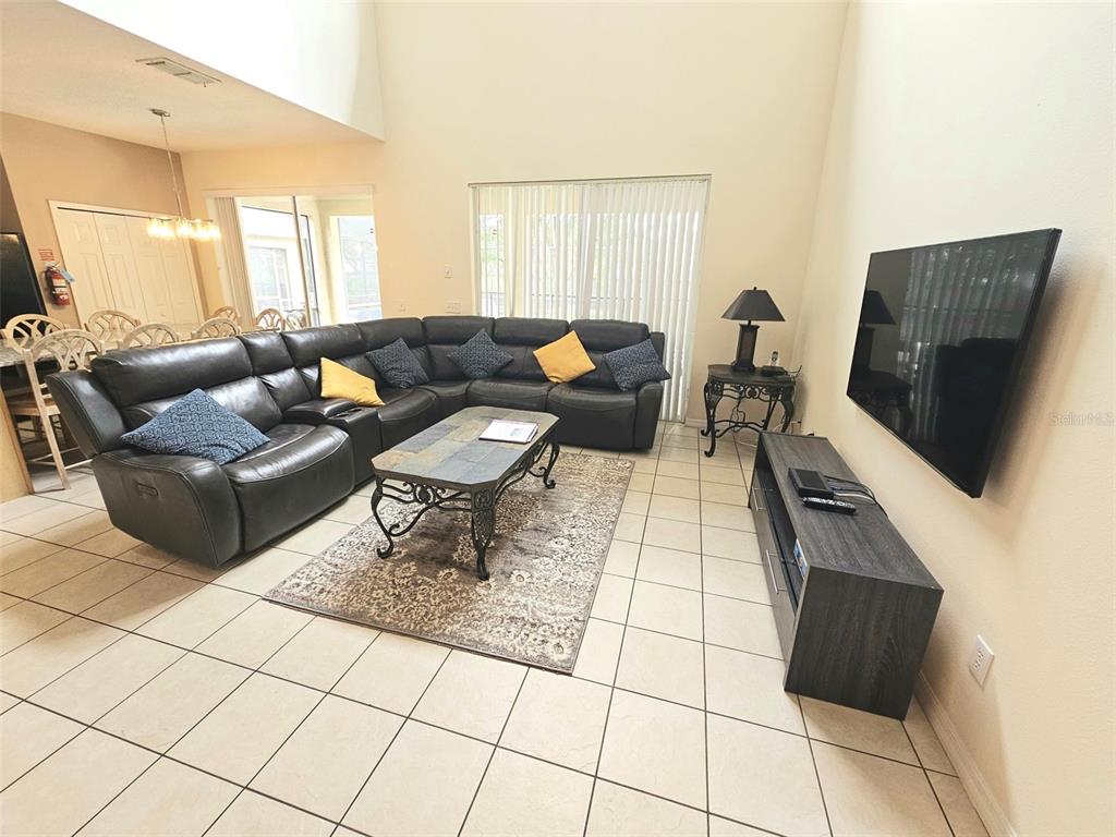 A living room features a large sectional sofa, a coffee table, and a wall-mounted television — 207 HIDEAWAY BEACH LANE, KISSIMMEE, FL