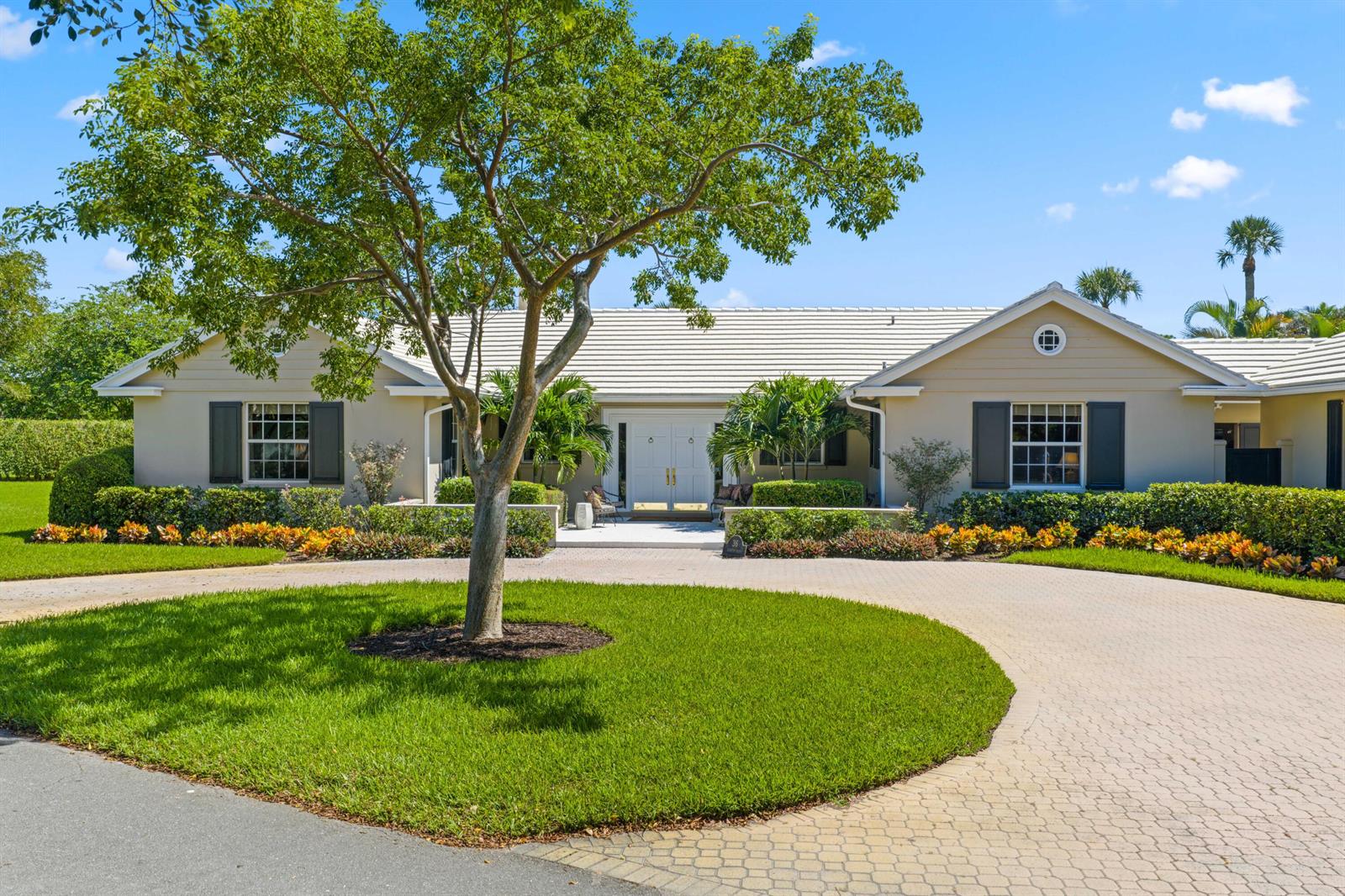 A single-story house with a circular paver driveway, a large tree, and manicured landscaping — 36 Country Road, FL 33436, FL