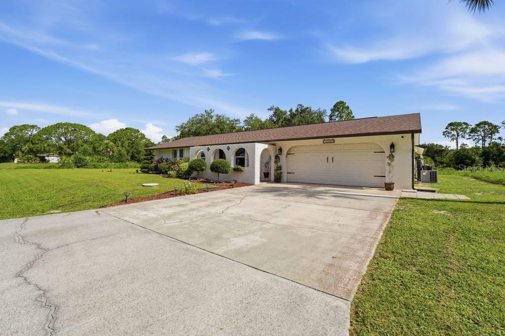 A single-story house with a white stucco exterior, a brown roof, and a two-car garage — 15562 MAYNARD AVENUE, PORT CHARLOTTE, FL