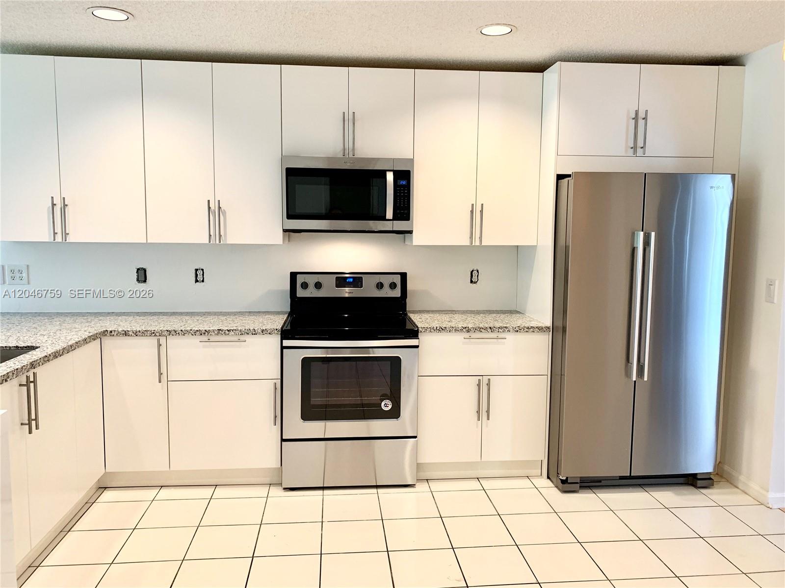 An entryway with white tile flooring leads into a living room with wood flooring — 2444 Stonegate Dr, Wellington FL 33414, WELLINGTON, FL