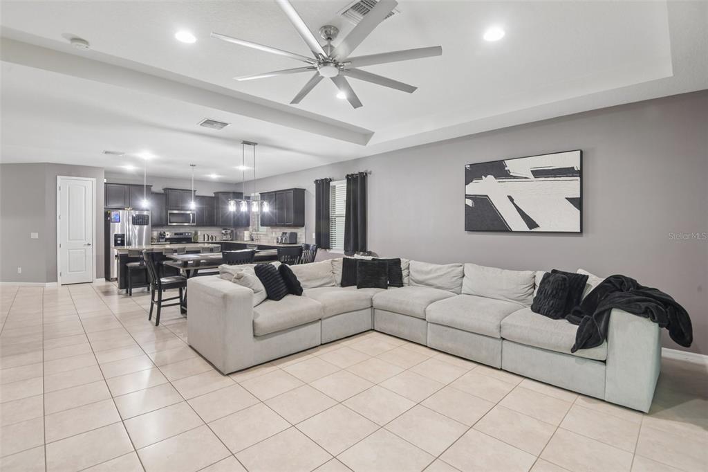 A spacious open-concept living room features a large sectional sofa, tile flooring, and kitchen area — 5319 FALLEN LEAF DRIVE, RIVERVIEW, FL