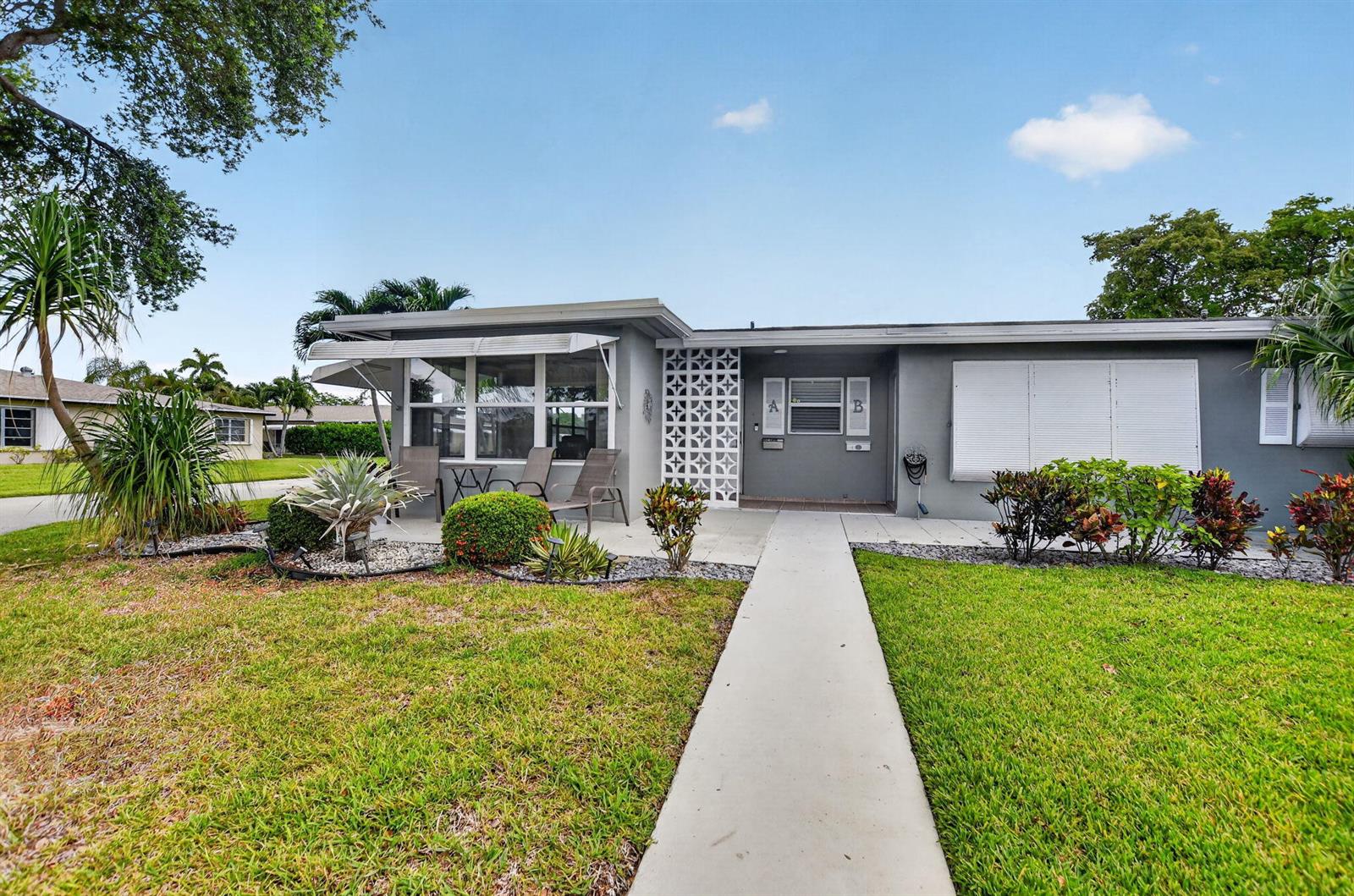 A single-story gray house with a concrete walkway, decorative screen wall, and front patio — 920 South Drive # A, Delray Beach FL 33445, DELRAY BEACH, FL