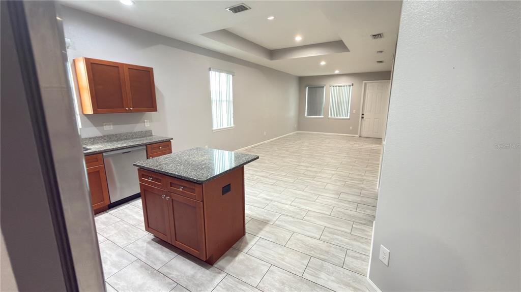A kitchen with a granite-topped island and wood cabinets opens into a spacious living area — 2704 W SAINT CONRAD STREET, TAMPA, FL