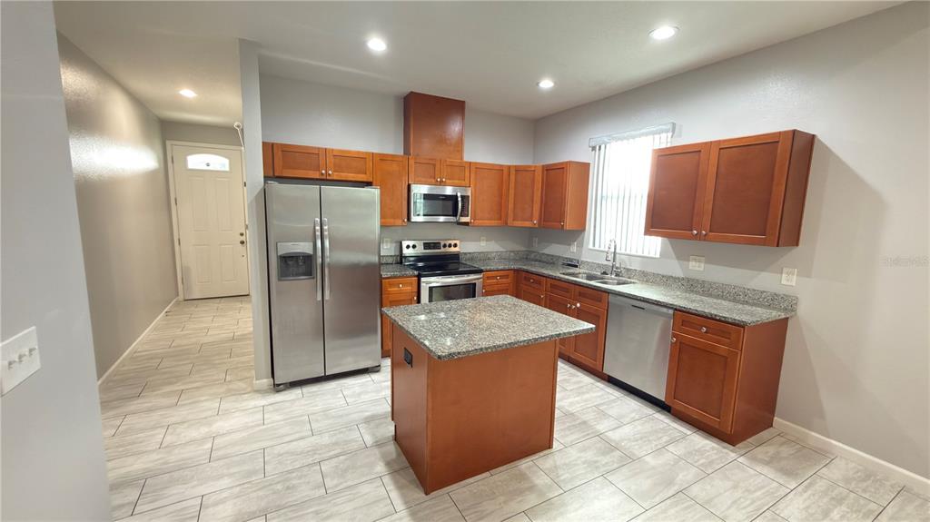 A kitchen features wood cabinets, granite countertops, stainless steel appliances, and a central island — 2704 W SAINT CONRAD STREET, TAMPA, FL