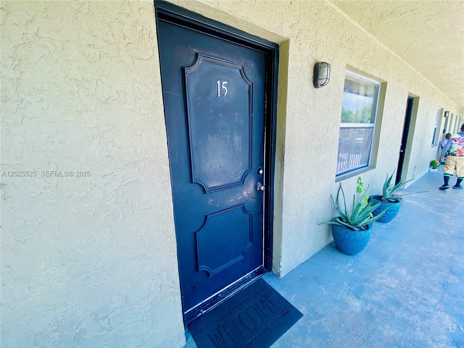 A dark blue door with the number 15 sits on a textured exterior walkway — 1702 S Dixie Hwy # 15, Lake Worth FL 33460, LAKE WORTH, FL