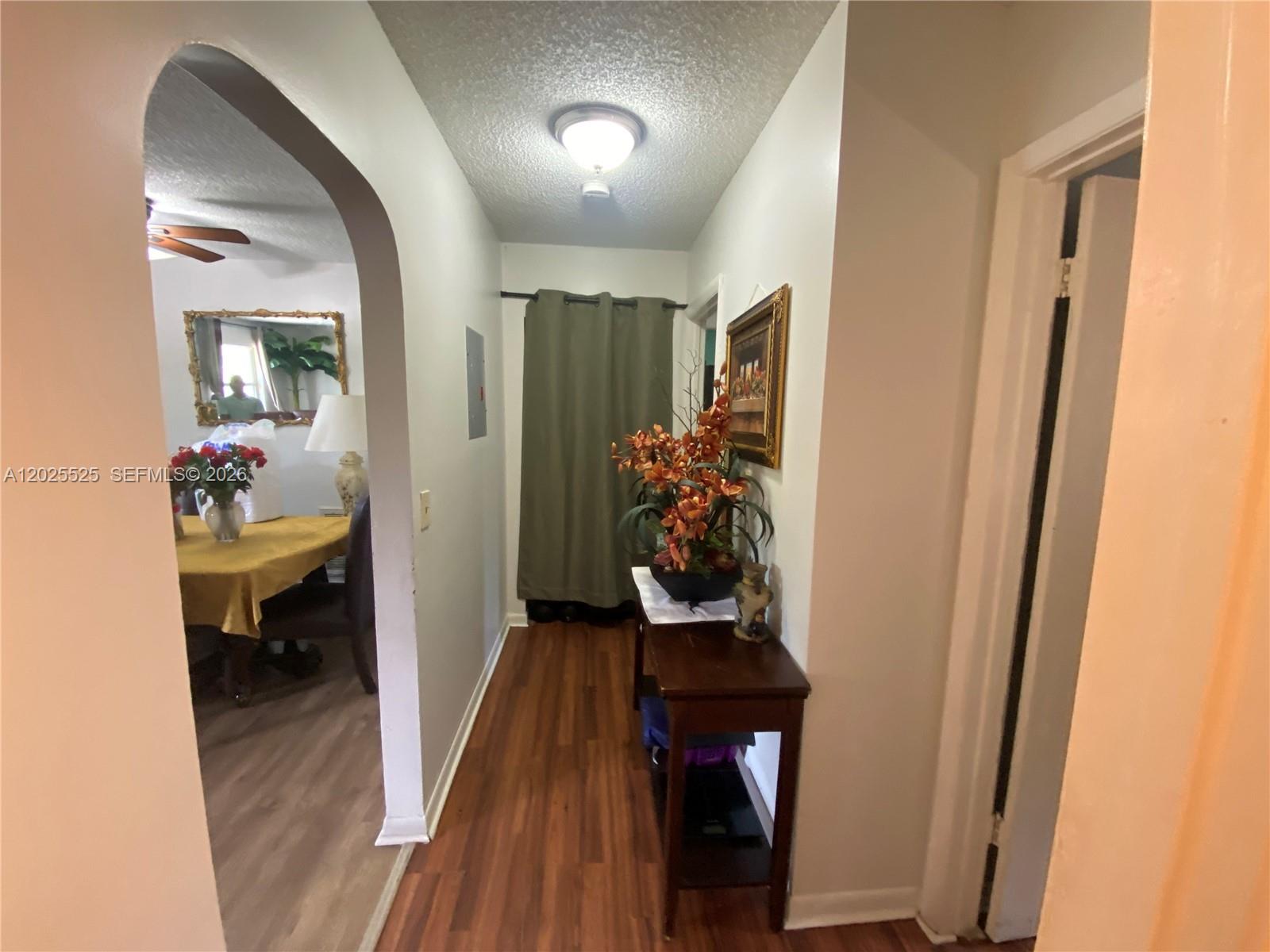 A hallway with wood-look flooring leads to a curtained doorway and an arched dining room — 1702 S Dixie Hwy # 15, Lake Worth FL 33460, LAKE WORTH, FL