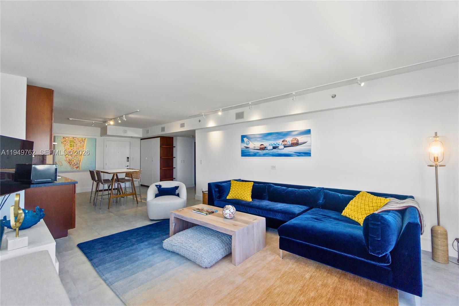 A living room features a blue velvet sectional sofa, a wooden coffee table, and track lighting — 100 Lincoln Rd # 1447, Miami Beach FL 33139, MIAMI BEACH, FL