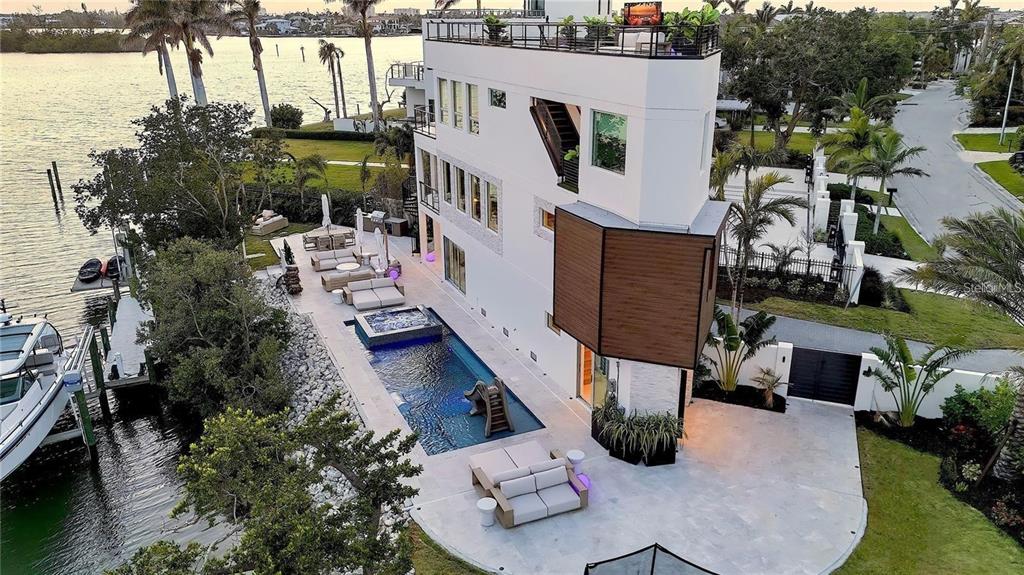 An aerial view of a modern multi-story home with a pool, patio, and boat dock — 1406 TANGIER WAY, SARASOTA, FL