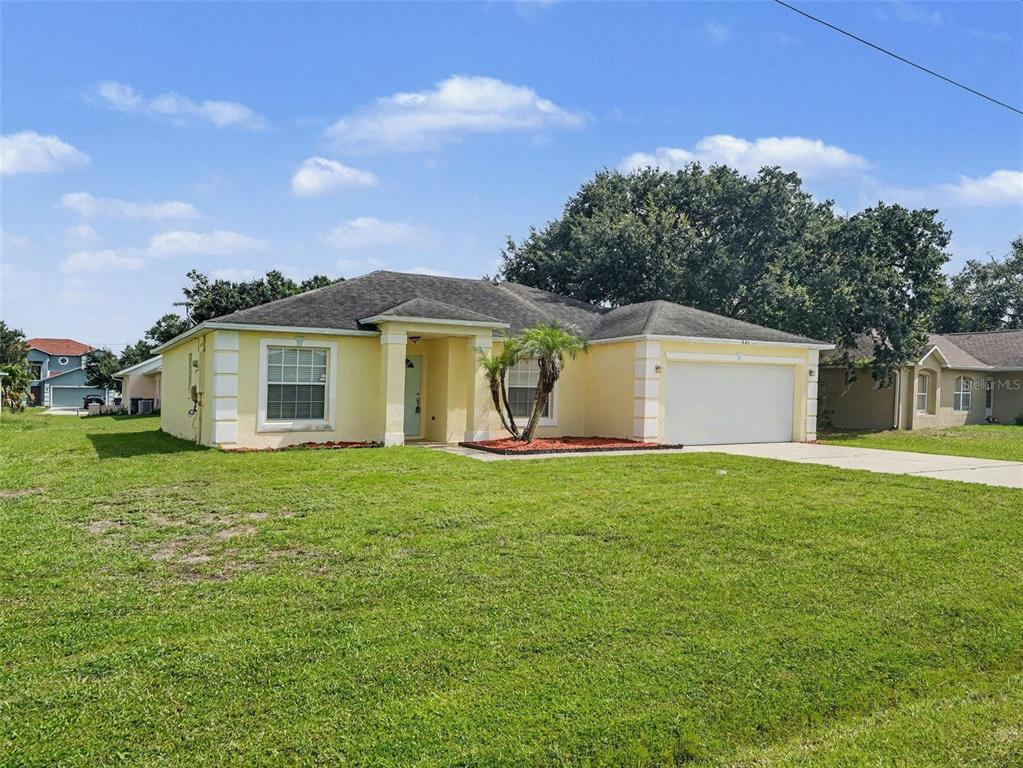 A yellow single-story house with a two-car garage and a front lawn — 521 EAGLE COURT, KISSIMMEE, FL