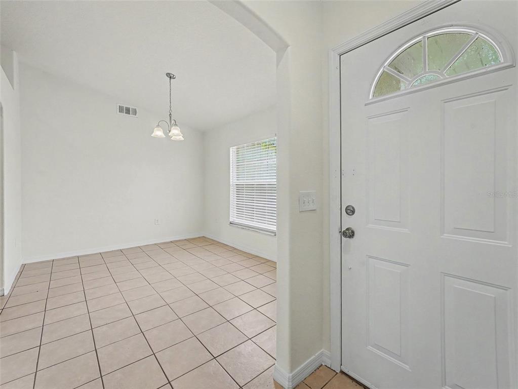 A tiled dining area features a white chandelier and a window with blinds — 521 EAGLE COURT, KISSIMMEE, FL