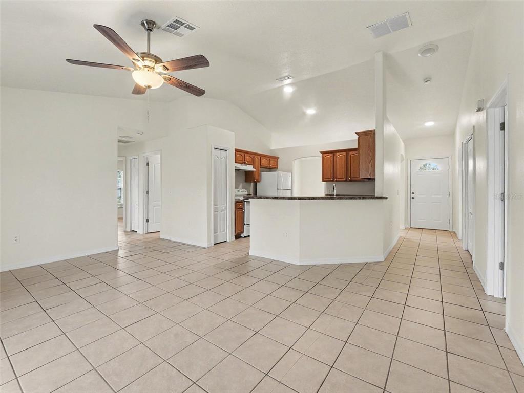 A tiled living area opens to a kitchen with wood cabinets and a breakfast bar — 521 EAGLE COURT, KISSIMMEE, FL