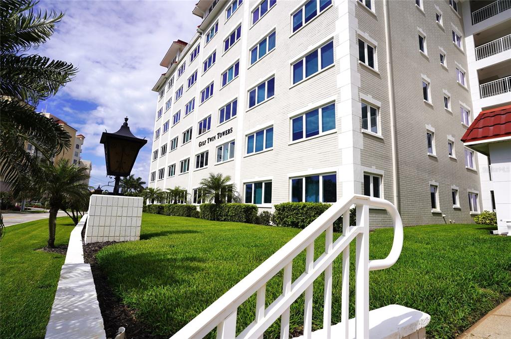 A low-angle exterior view of a multi-story white brick building labeled Gulf Twin Towers — 500 THE ESPLANADE N UNIT 604, VENICE, FL