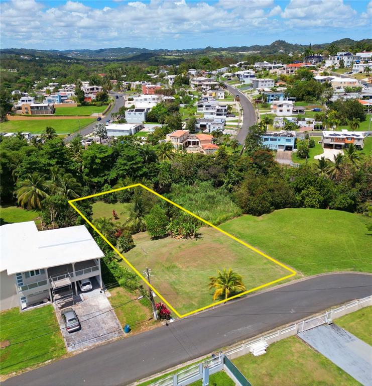 An aerial view shows a vacant, rectangular residential lot outlined in yellow near a road — CALLE CEMI URB. HACIENDAS DEL CARIBE UNIT B6, TOA ALTA, PR