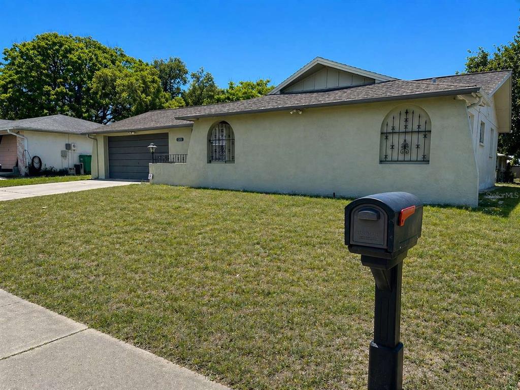 A single-story house with a beige stucco exterior, a gray garage door, and arched windows — 7210 SAN MORITZ DRIVE, PORT RICHEY, FL