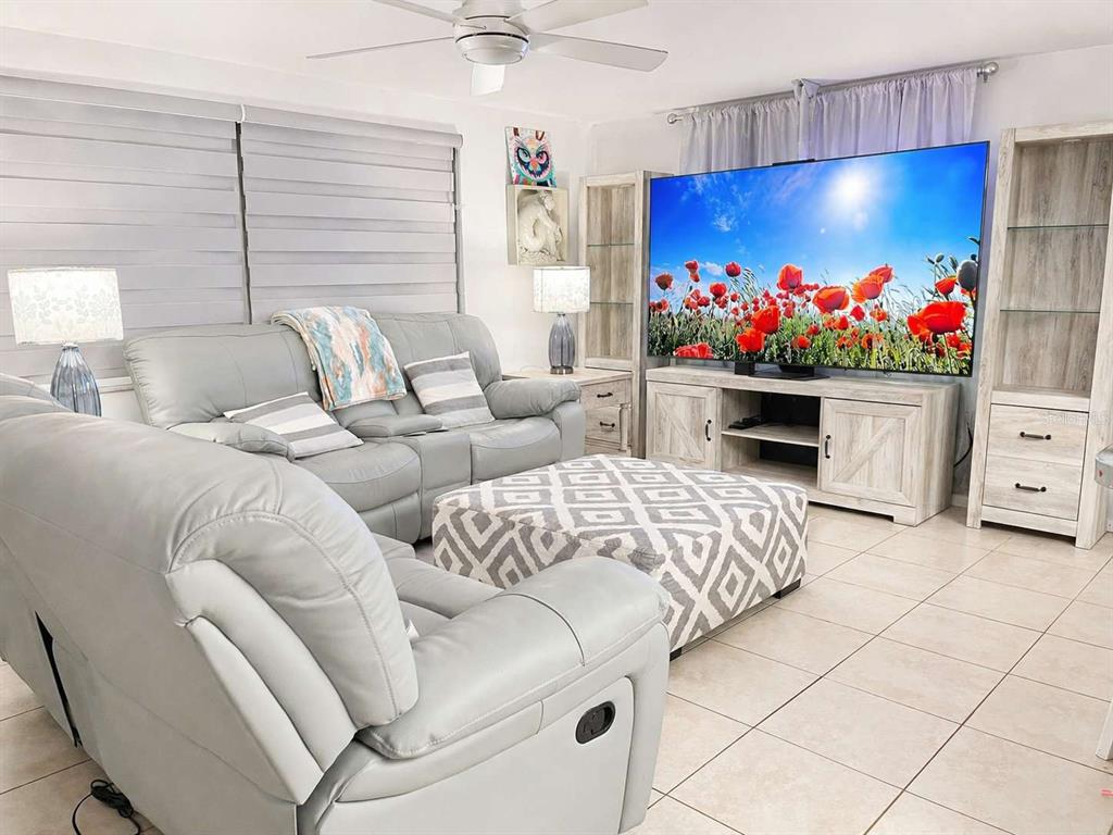 A living room features light gray leather furniture, a patterned ottoman, and a large television — 7210 SAN MORITZ DRIVE, PORT RICHEY, FL