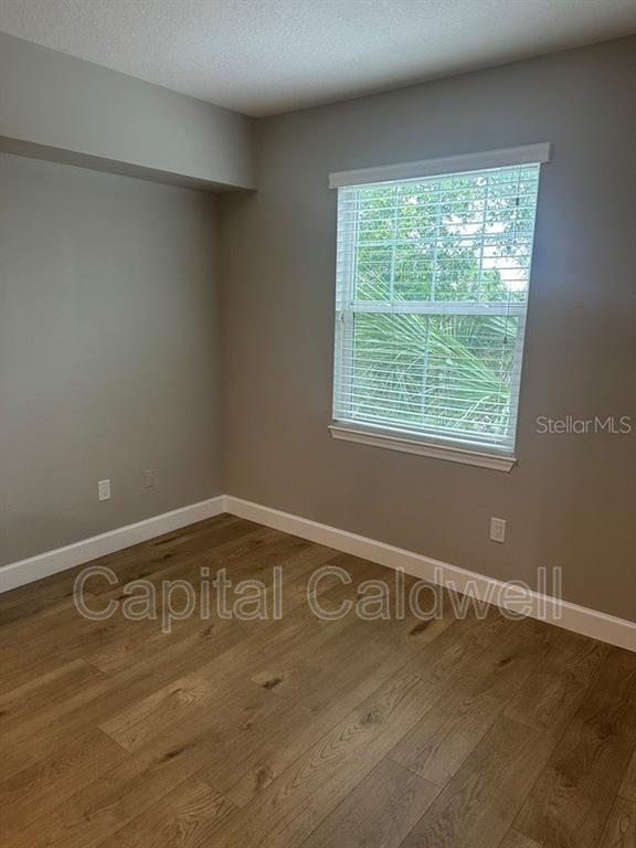 An empty bedroom features light wood-look flooring, gray walls, and a window with blinds — 2010 E PALM AVE UNIT 15306, TAMPA, FL