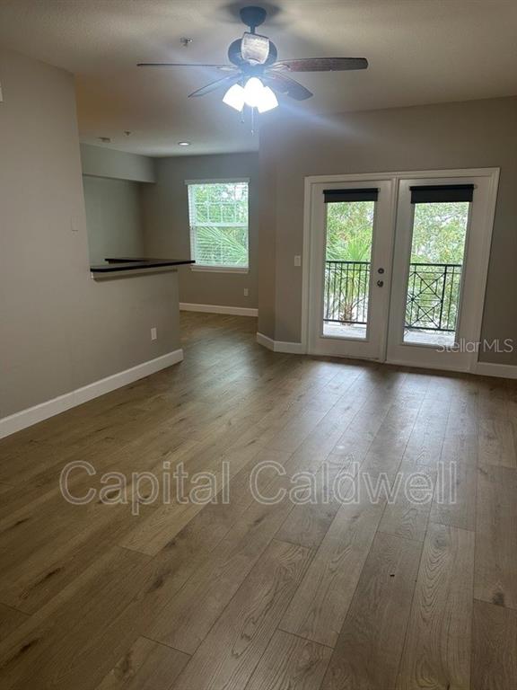 A living room with wood-look flooring, a ceiling fan, and glass doors leading to a balcony — 2010 E PALM AVE UNIT 15306, TAMPA, FL
