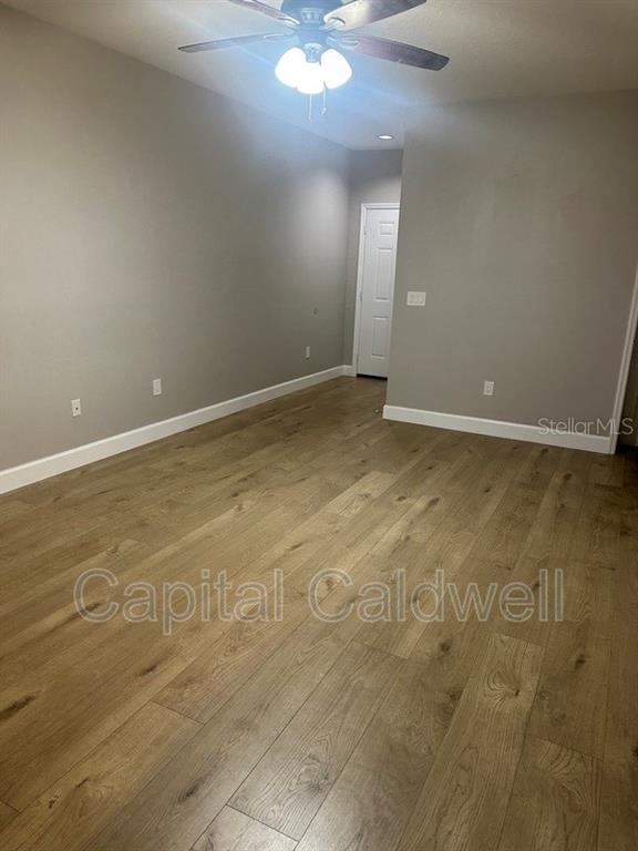 An empty room features light gray walls, wood-look flooring, and a ceiling fan — 2010 E PALM AVE UNIT 15306, TAMPA, FL