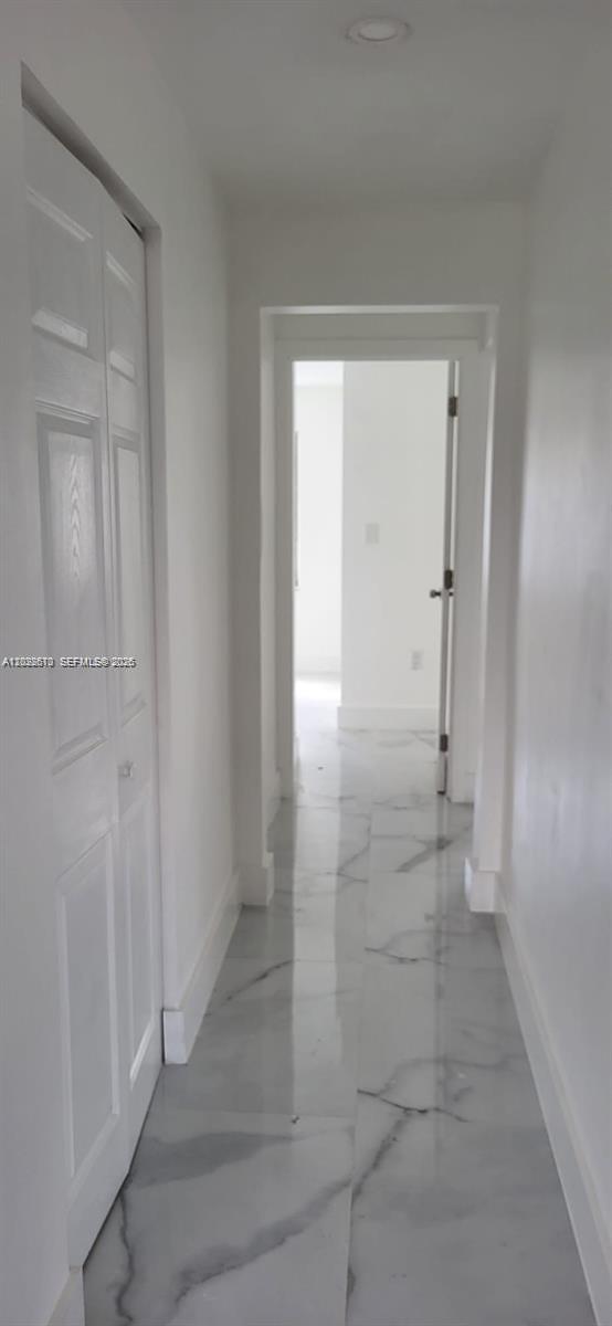 A narrow hallway features white walls, a closet with bifold doors, and polished marble flooring — 712 Hialeah Dr, Hialeah FL 33010, HIALEAH, FL