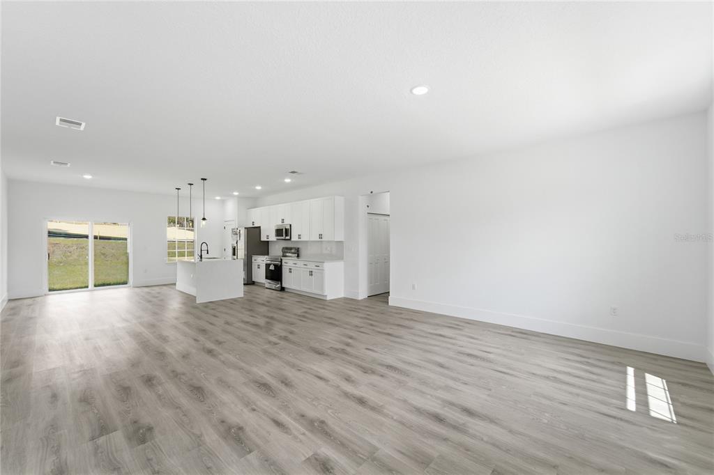 A bright, open-concept kitchen and living area featuring white cabinetry, an island, and wood-look flooring — 2861 W DELLWOOD STREET, CITRUS SPRINGS, FL