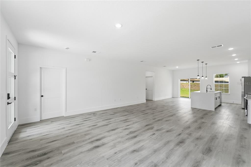 An open-concept living area features white walls, light gray wood-look flooring, and a kitchen island — 2861 W DELLWOOD STREET, CITRUS SPRINGS, FL