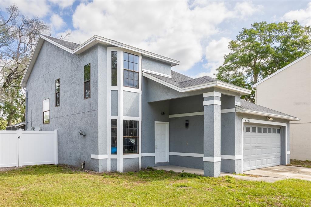A two-story gray stucco house with a white front door and a one-car garage — 4226 CLOVERLEAF PLACE, CASSELBERRY, FL