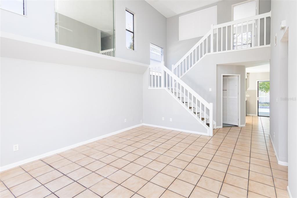 An empty room with tiled floors, a staircase, and a high ceiling — 4226 CLOVERLEAF PLACE, CASSELBERRY, FL