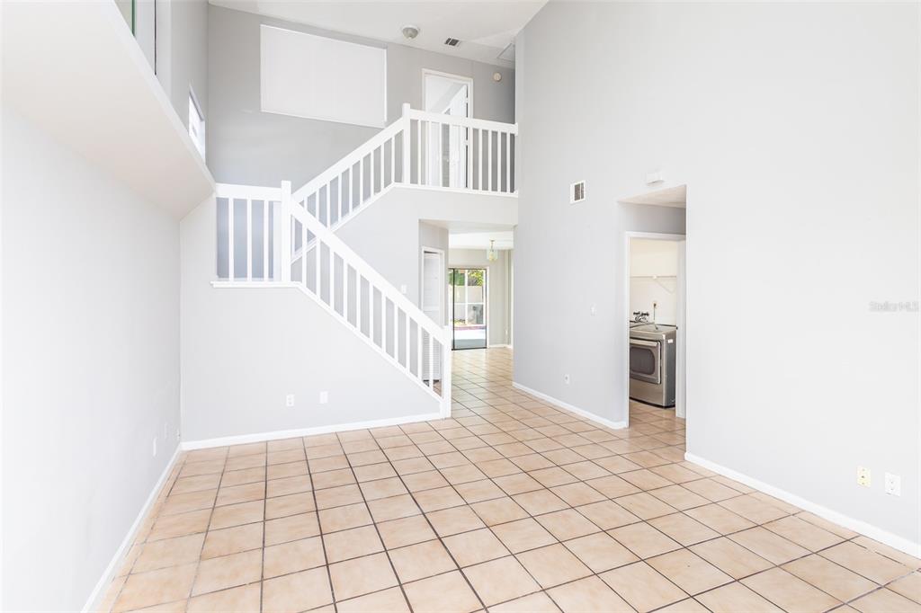 A bright, open-concept living area features tile flooring, a staircase, and a view toward the kitchen — 4226 CLOVERLEAF PLACE, CASSELBERRY, FL