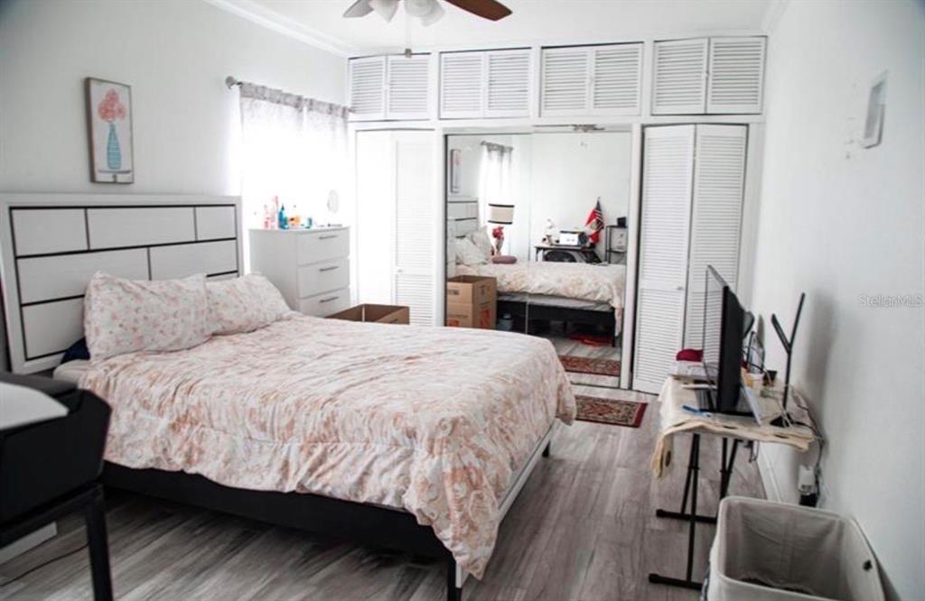 A bedroom features a bed with floral bedding, mirrored closet doors, and light wood flooring — 2503 W MARQUETTE AVENUE, TAMPA, FL