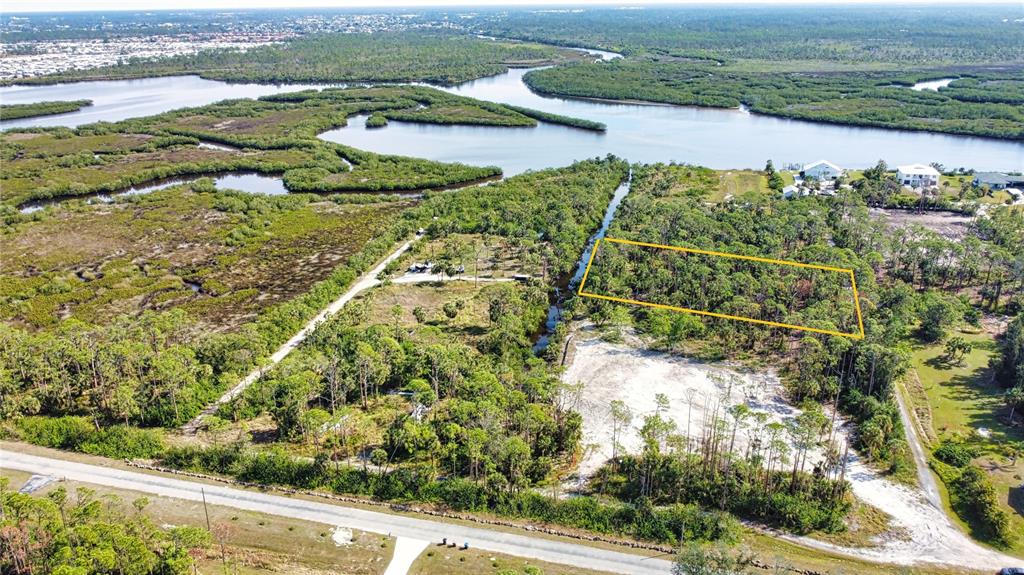 An aerial view shows a rectangular plot of land highlighted in yellow near a waterway — 9051 CALOOSA DRIVE, VENICE, FL