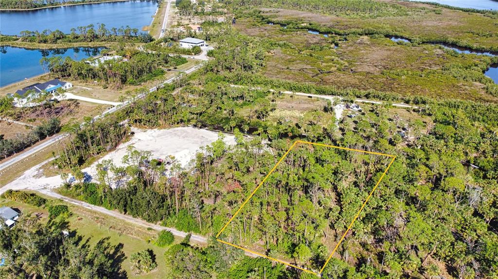 An aerial view shows a rectangular, wooded lot outlined in yellow near a residential area — 9051 CALOOSA DRIVE, VENICE, FL