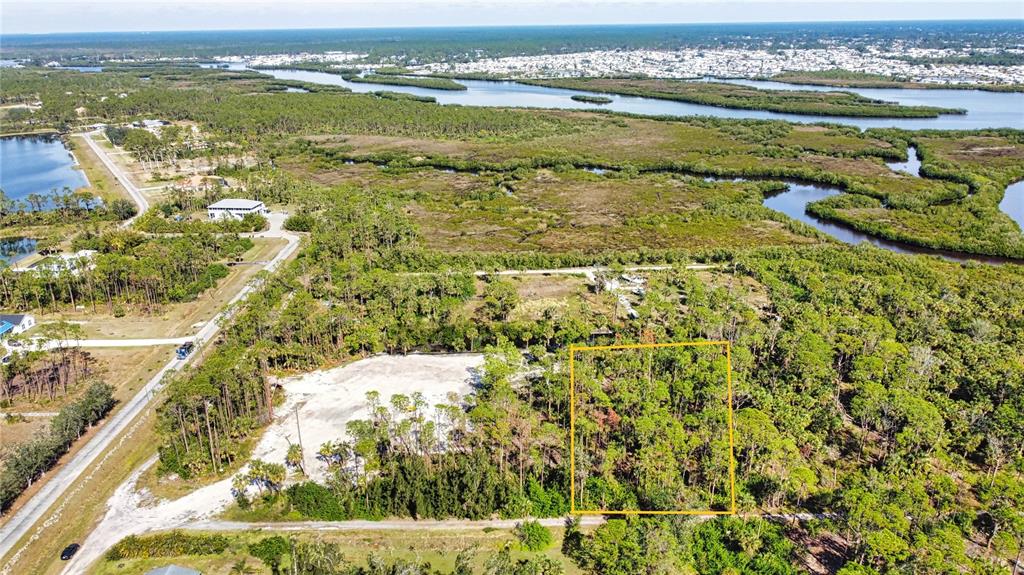 An aerial view shows a rectangular plot of land outlined in yellow amidst wooded terrain — 9051 CALOOSA DRIVE, VENICE, FL