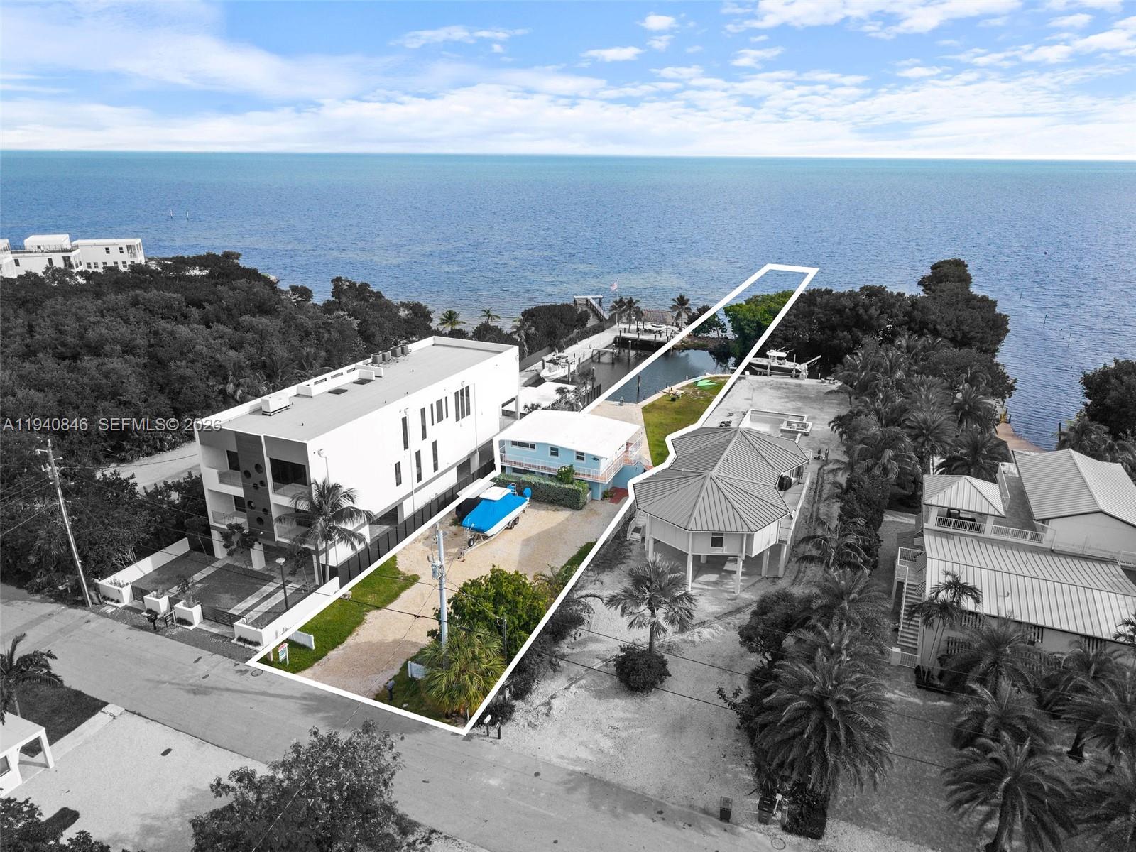 An aerial view shows a waterfront property with a house, boat, and private dock — 127 Seaside Ave, Key Largo FL 33037, KEY LARGO, FL