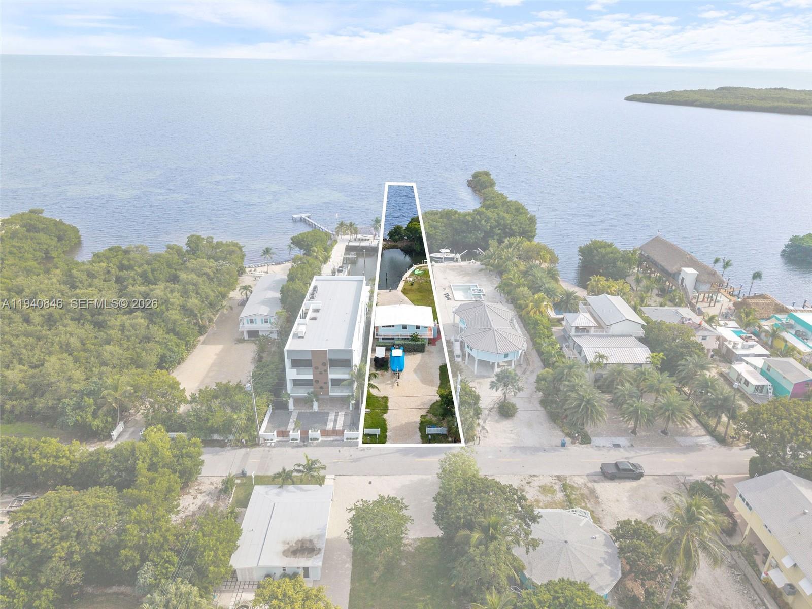 An aerial view shows a waterfront property with a boat slip and a small house — 127 Seaside Ave, Key Largo FL 33037, KEY LARGO, FL