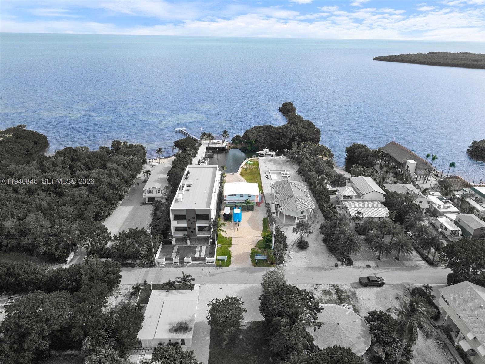 An aerial view shows waterfront properties with a boat dock, vegetation, and a road — 127 Seaside Ave, Key Largo FL 33037, KEY LARGO, FL