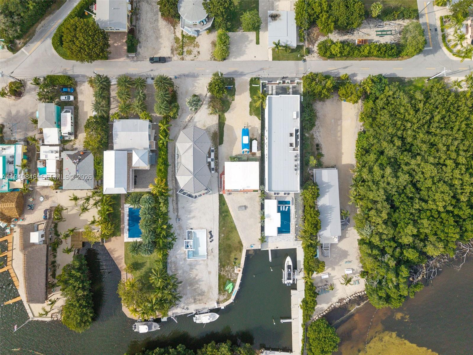 Aerial view of waterfront properties featuring swimming pools, boat docks, and lush vegetation — 127 Seaside Ave, Key Largo FL 33037, KEY LARGO, FL