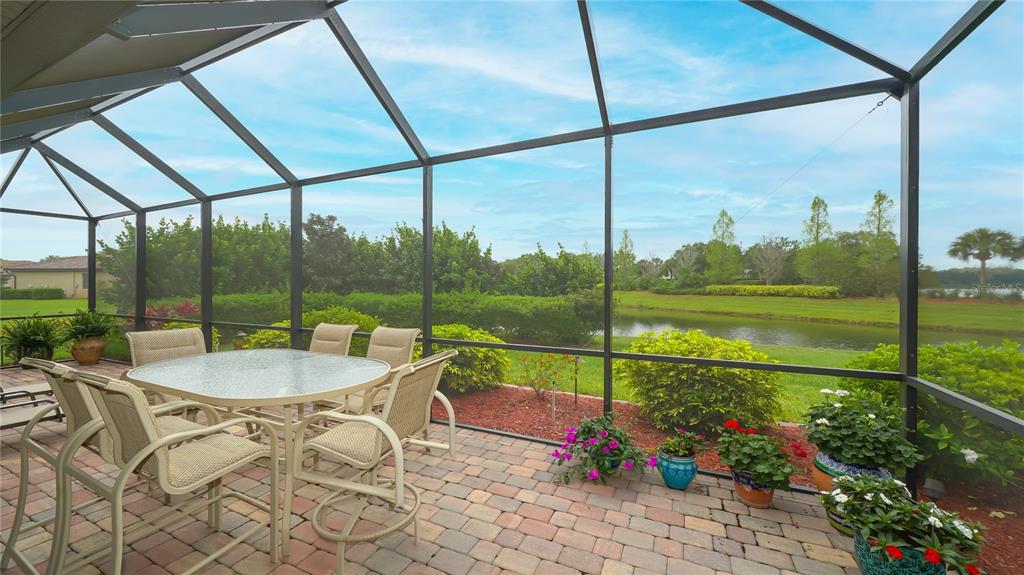 A screened-in patio with a dining set overlooks a grassy lawn and a small pond — 6888 WILLOWSHIRE WAY, BRADENTON, FL