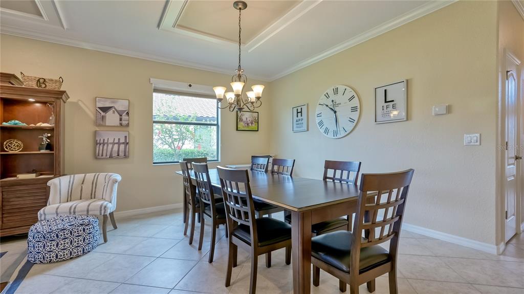 A dining room features a wooden table, six chairs, a chandelier, and wall decor — 6888 WILLOWSHIRE WAY, BRADENTON, FL