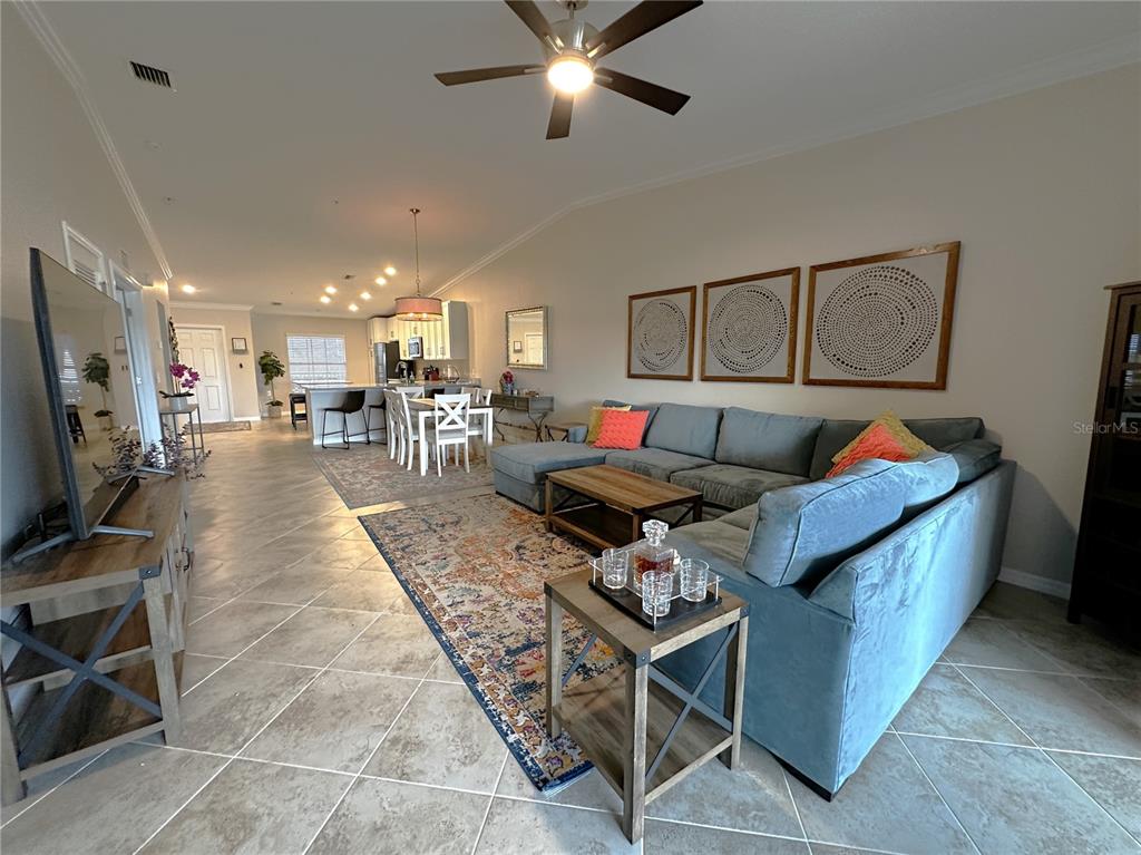 An open-concept living room features a large blue sectional sofa, tile flooring, and a kitchen — 14050 HERITAGE LANDING BOULEVARD UNIT 226, PUNTA GORDA, FL