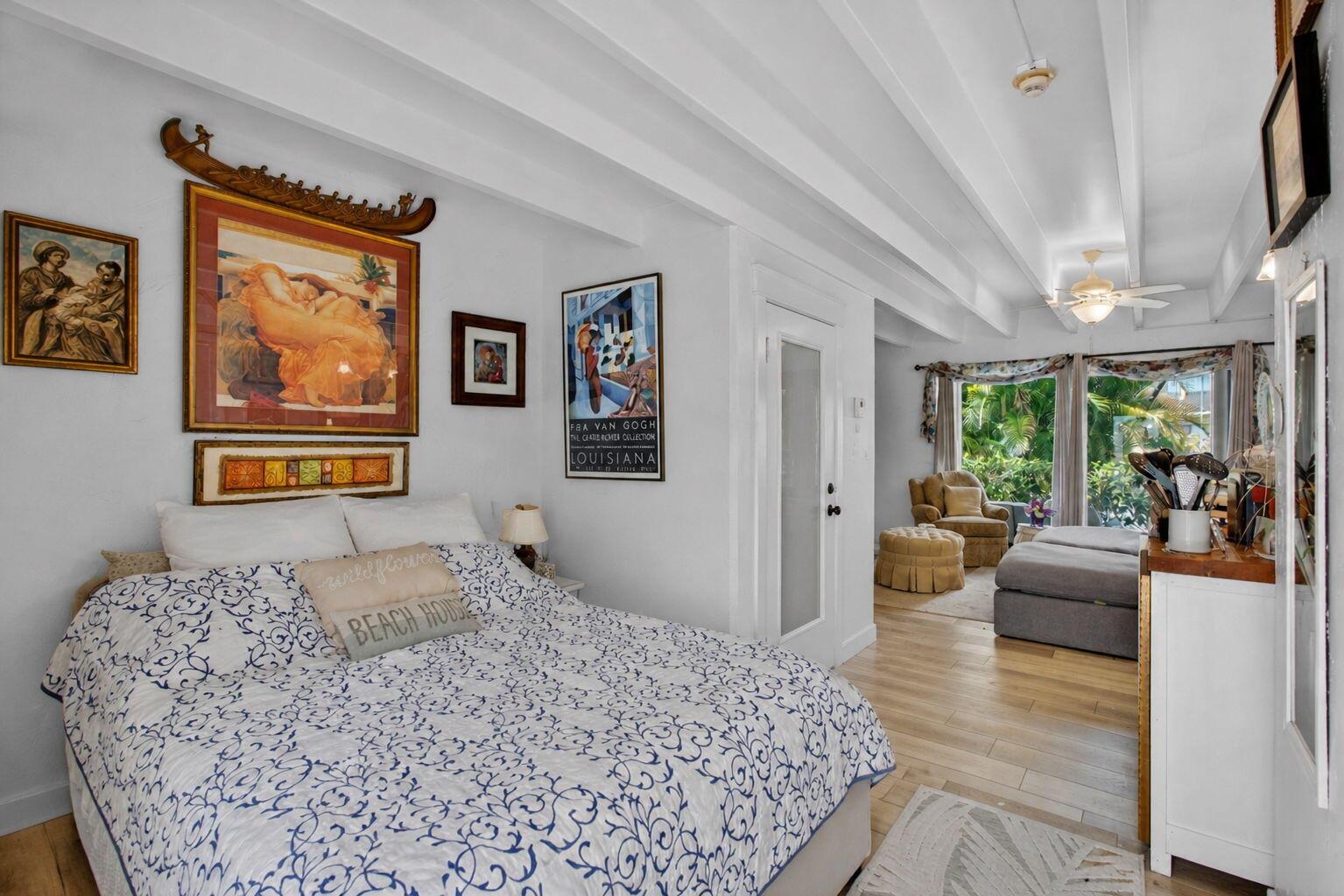 A bedroom with a patterned bedspread, framed artwork, and an adjacent seating area with windows — 4001 S Ocean Boulevard # 111, Palm Beach FL 33480, PALM BEACH, FL